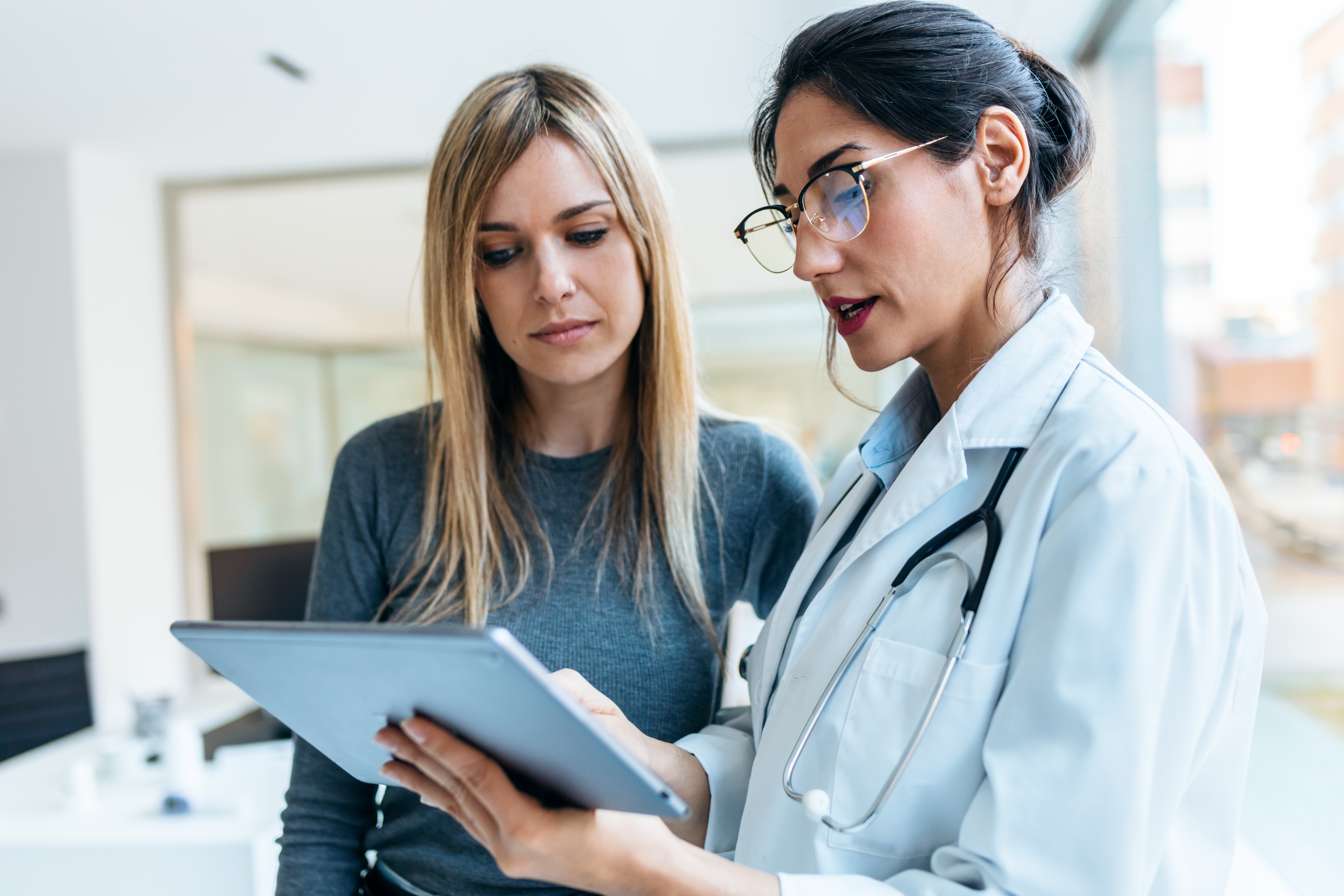 young woman meets with doctor reading clipboard
